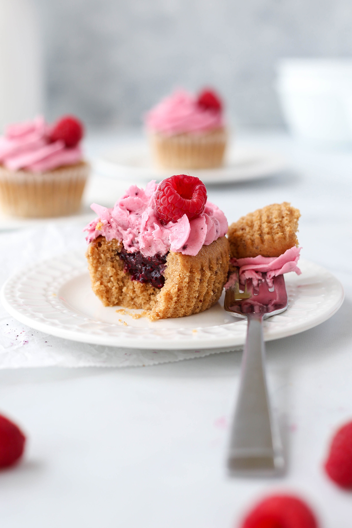 a lemon raspberry cupcake on a plate, showing the jam filling inside