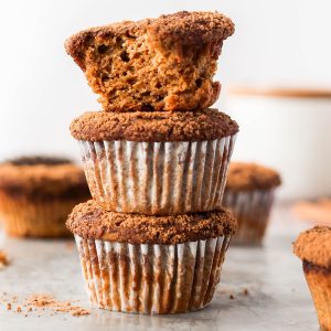 a stack of pumpkin protein muffins with a bite taken out