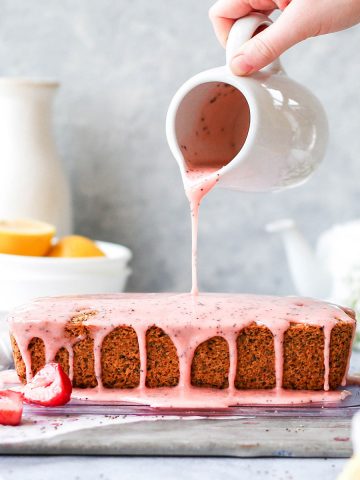 a strawberry loaf cake with strawberry glaze being poured on top