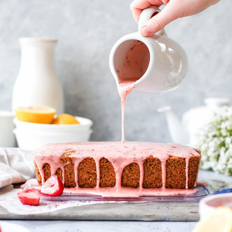 a strawberry loaf cake with strawberry glaze being poured on top