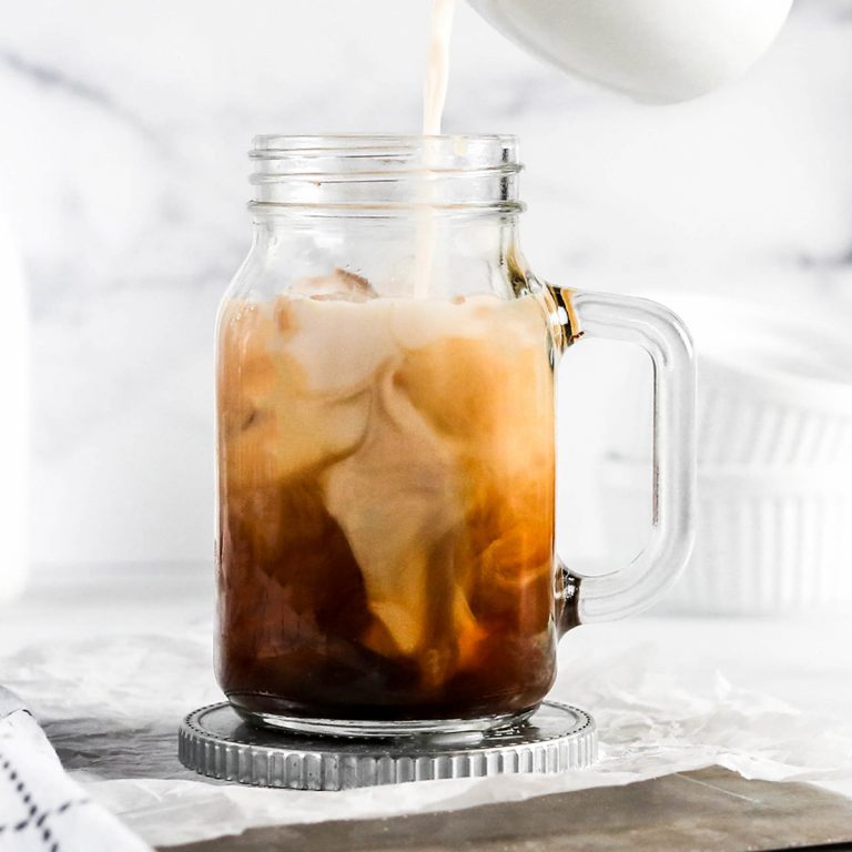 an almond milk latte with milk being poured into the glass