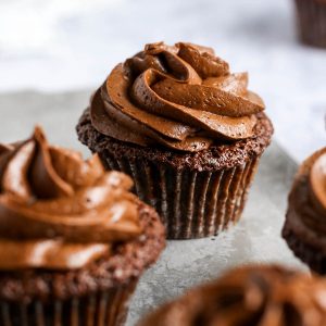 gluten free cupcakes on a grey tray, with chocolate frosting piped on top