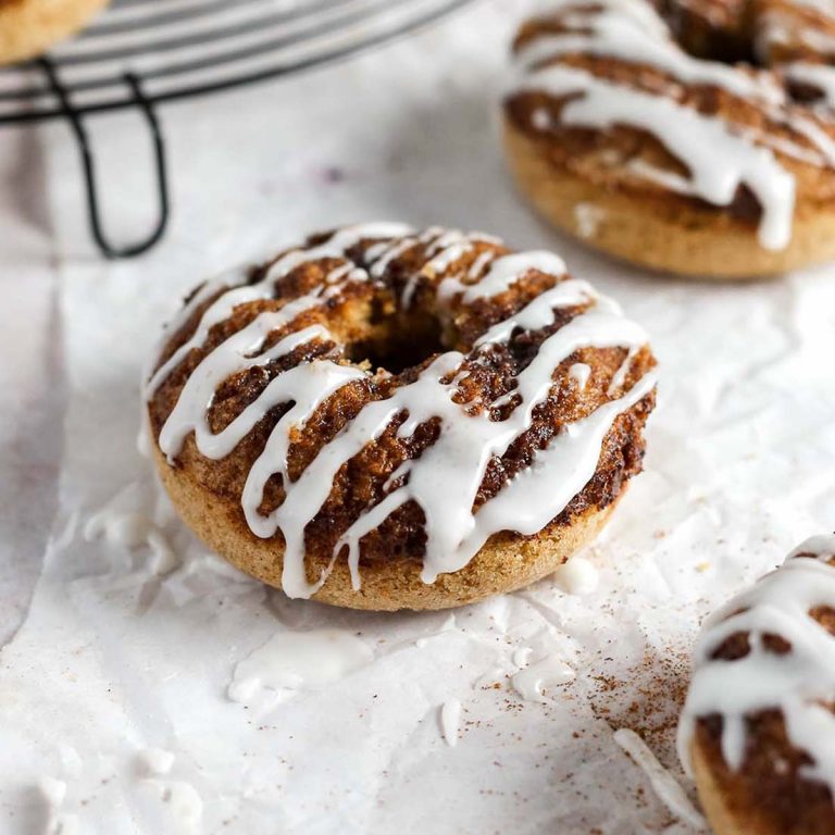 a cinnamon roll donut on parchment paper with a vanilla glaze on top