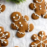 multiple gingerbread men cookies on parchment paper with frosting