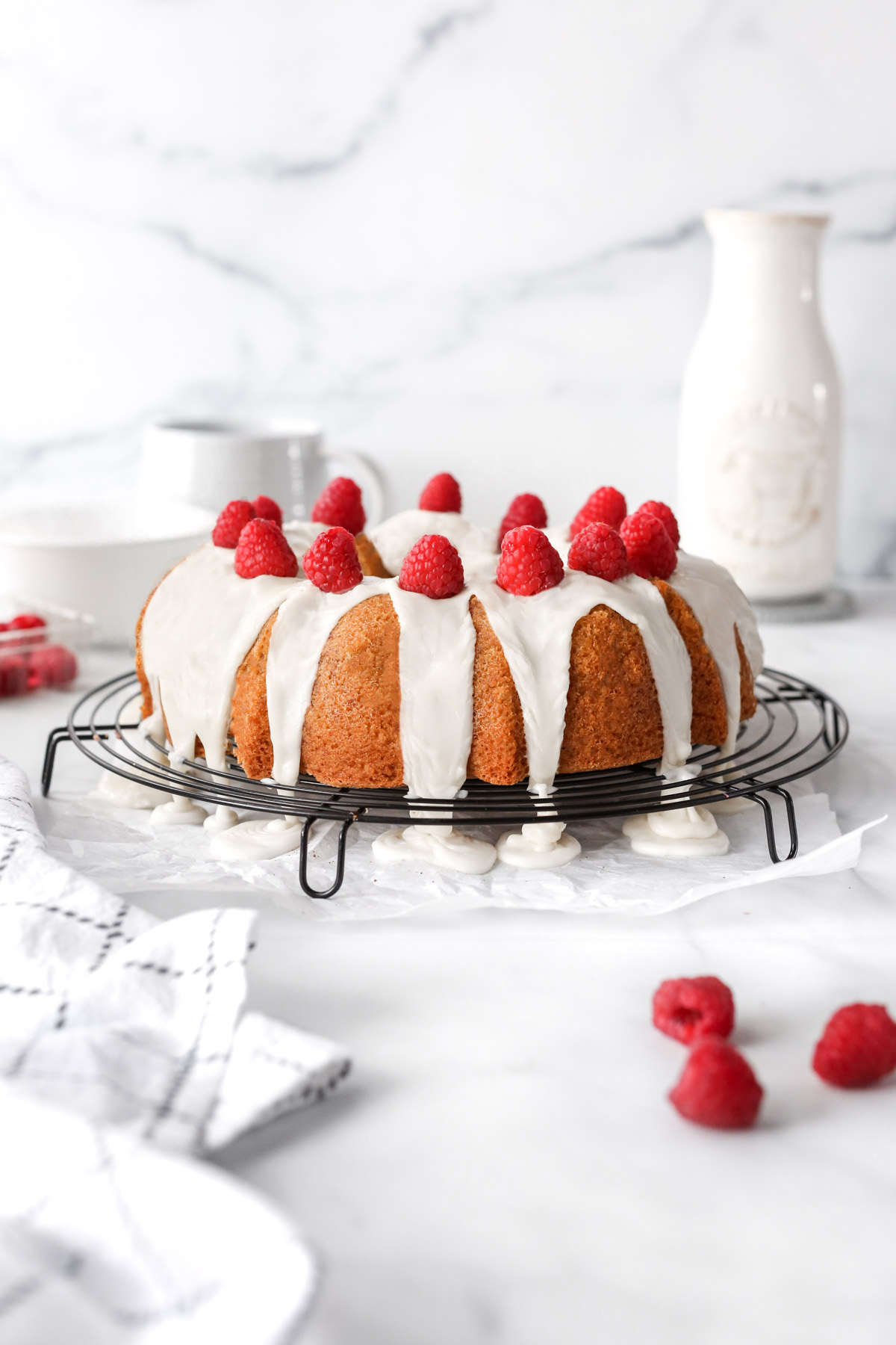 the finished raspberry white chocolate bundt cake with the ganache and fresh raspberries on top.