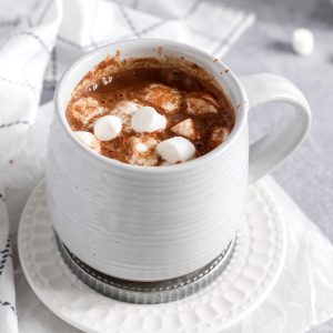 a grey mug with oat milk hot cocoa and marshmallows inside.