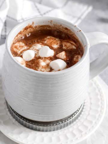 a grey mug with oat milk hot cocoa and marshmallows inside.