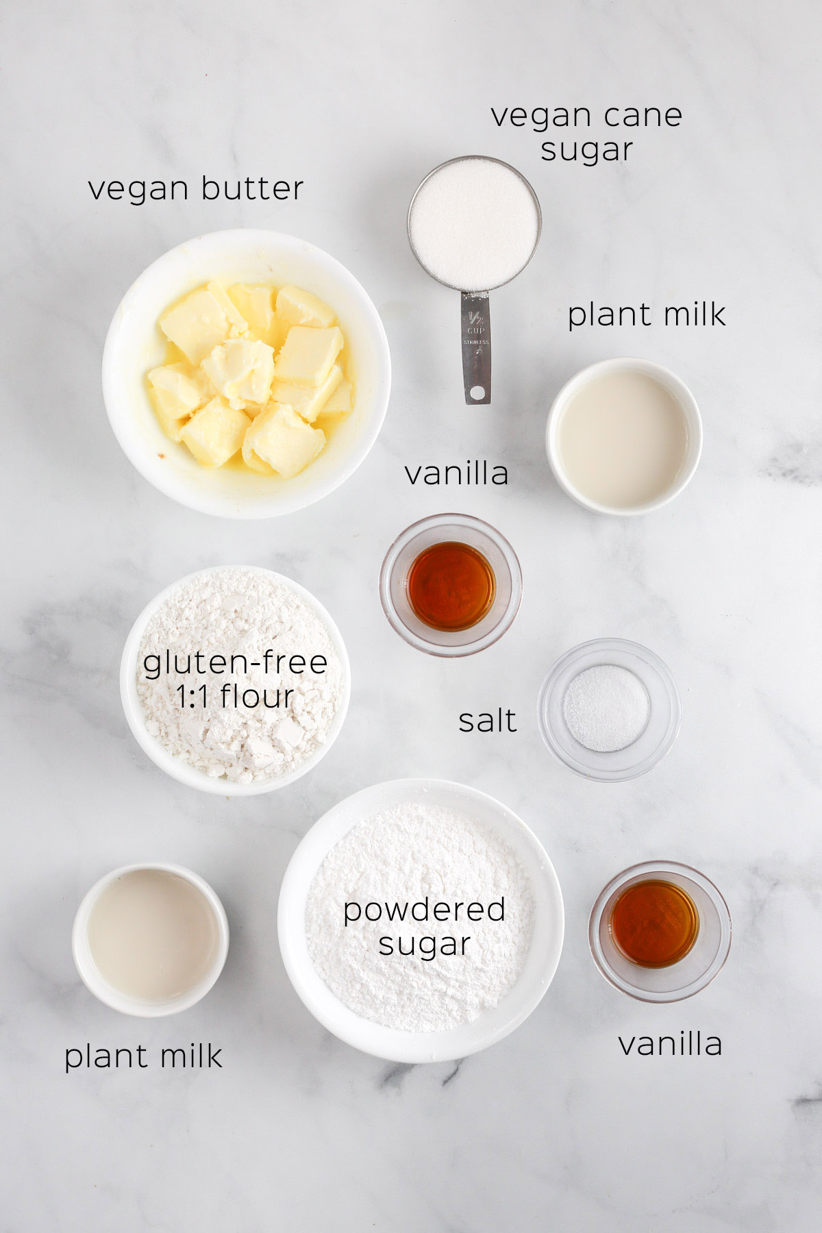 all of the ingredients needed to make the thumbprint cookies. Each ingredient is in a small bowl on a marble surface.