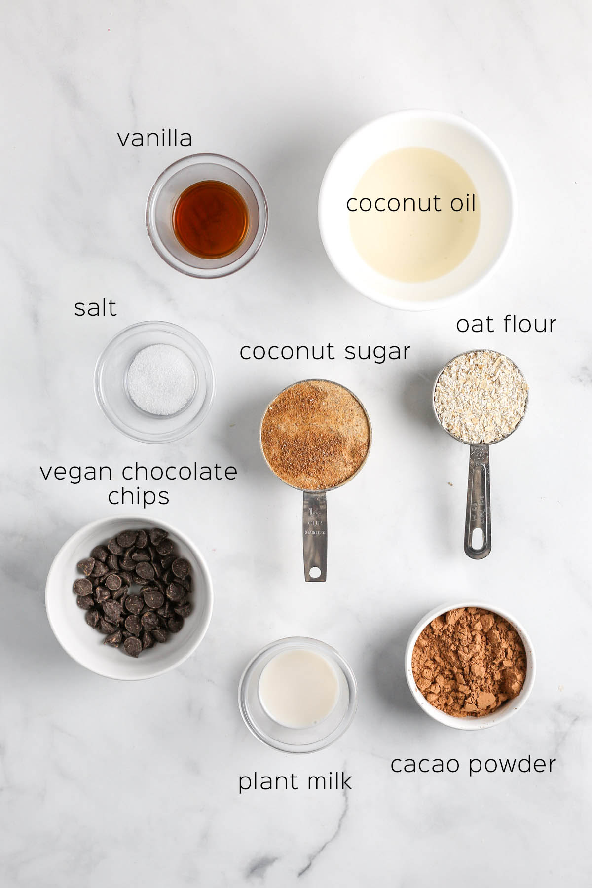all of the ingredients to make the brownie batter in small bowls on a marble surface.