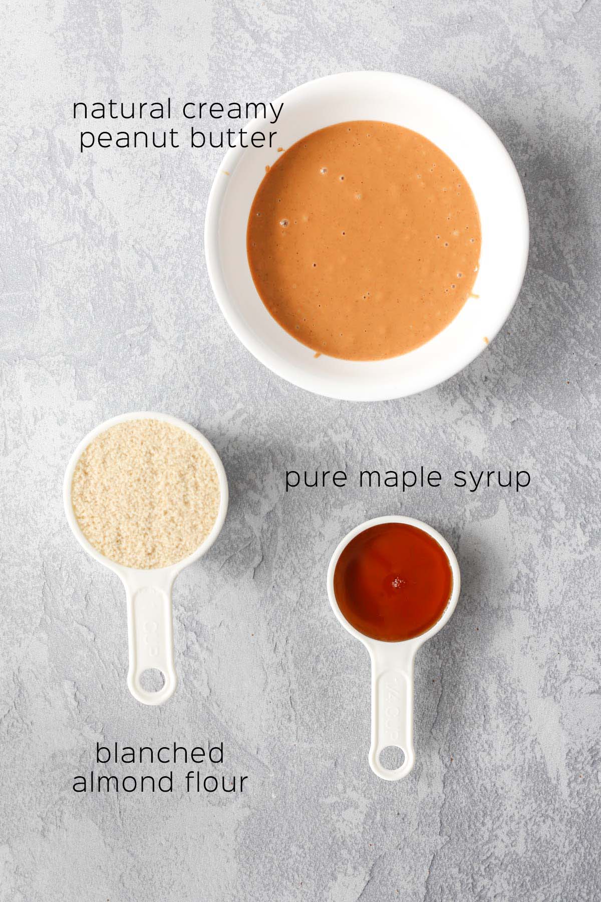 the ingredients needed to make the cookies, including peanut butter, almond flour, and maple syrup.