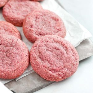 multiple pink sugar cookies on a baking tray