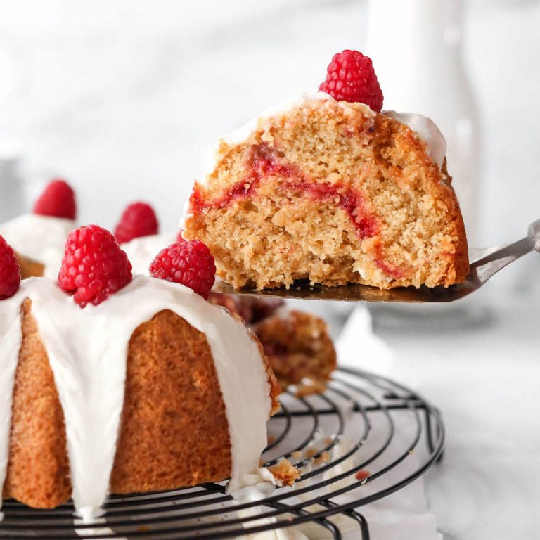 a slice of raspberry white chocolate bundt cake being removed from the tray