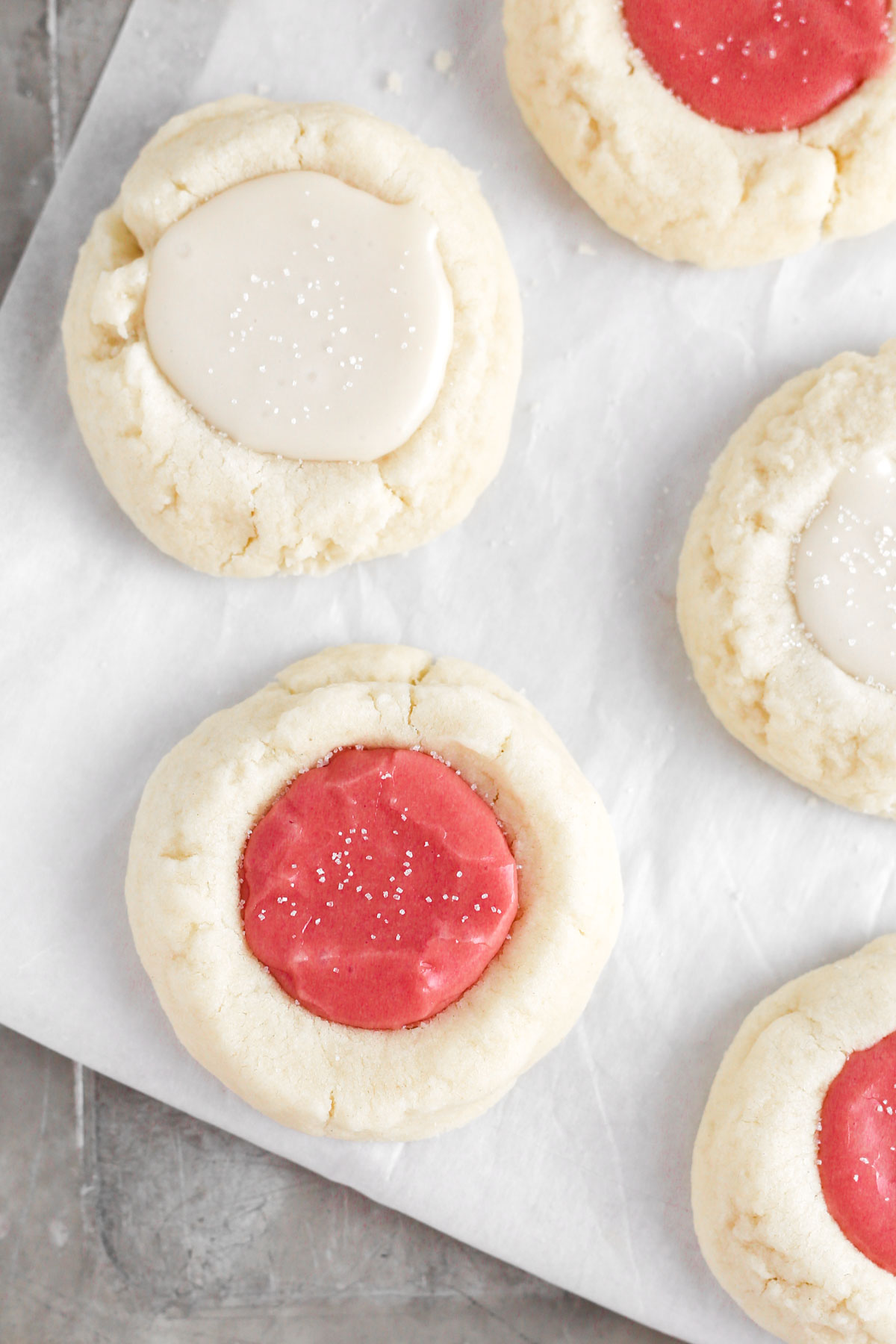 multiple thumbprint cookies with red and white icing in the center.