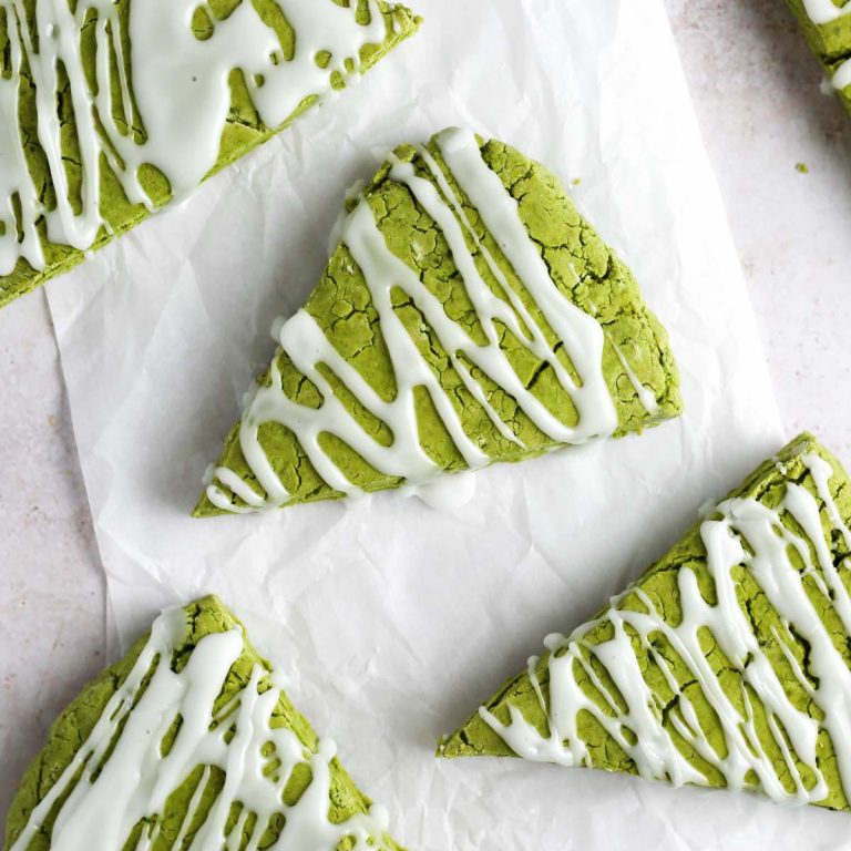 many green matcha scones on parchment paper with glaze.