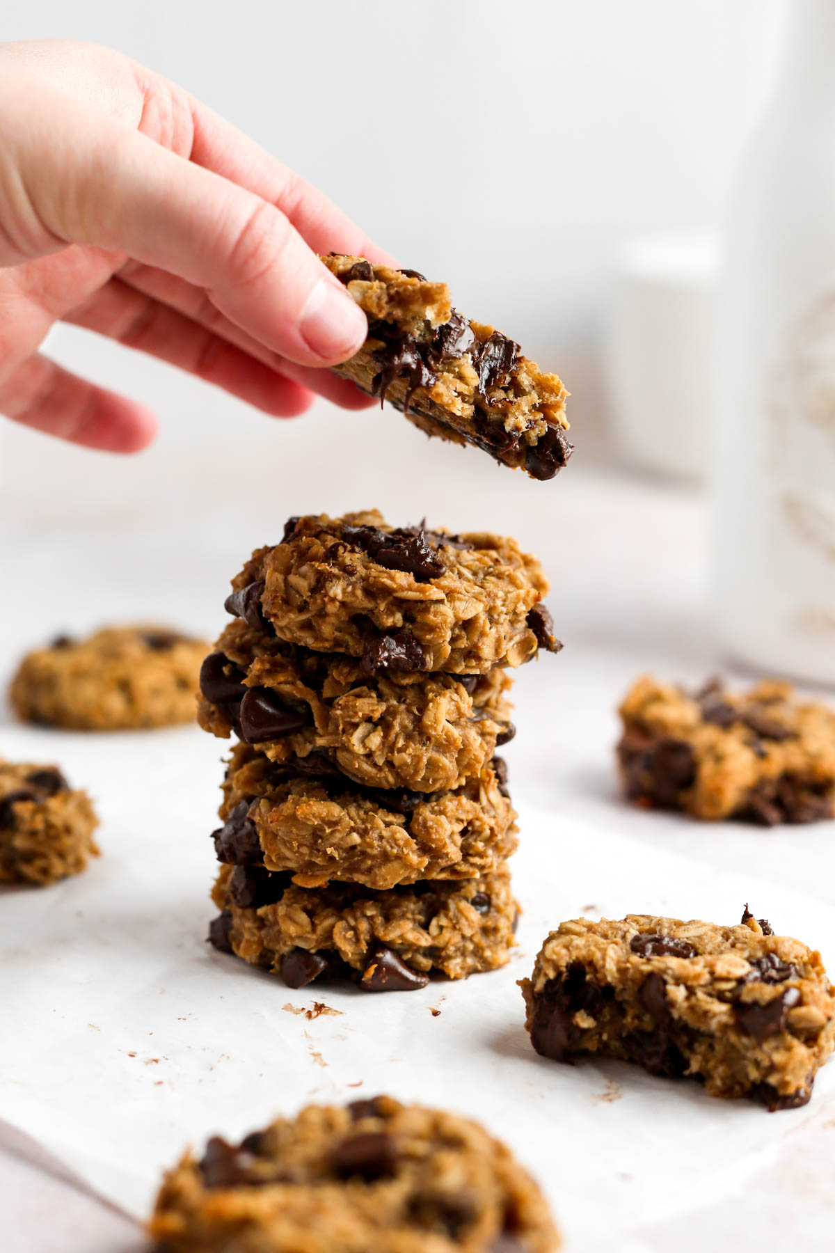 a stack of oatmeal cookies with someone picking up the top cookie off the stack.