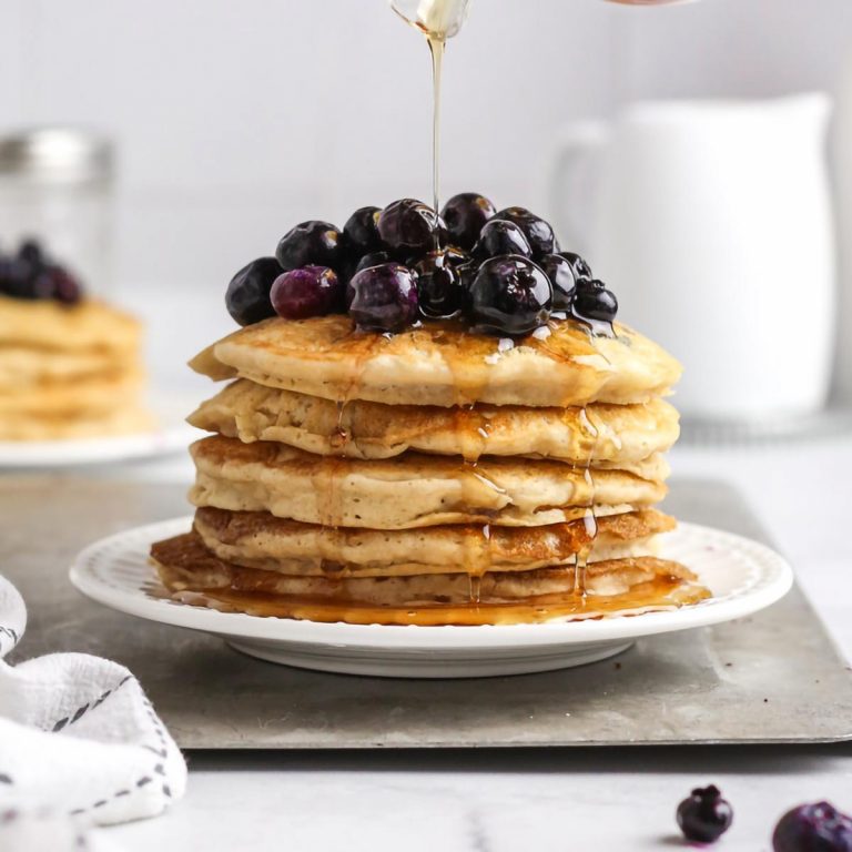vegan bisquick pancakes on a plate with fresh blueberries on top.