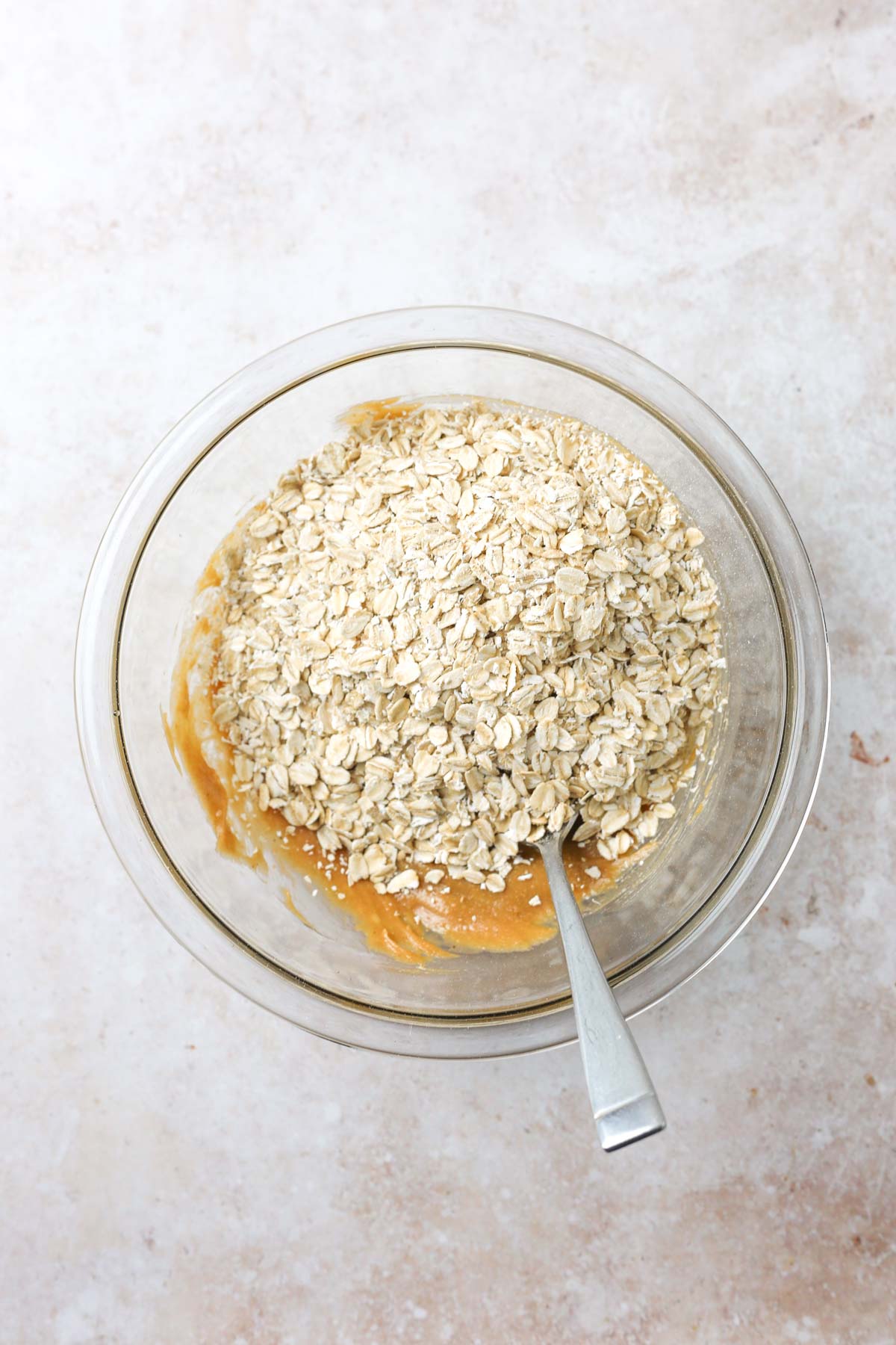 adding the old-fashioned oats to the bowl with the peanut butter and maple syrup.
