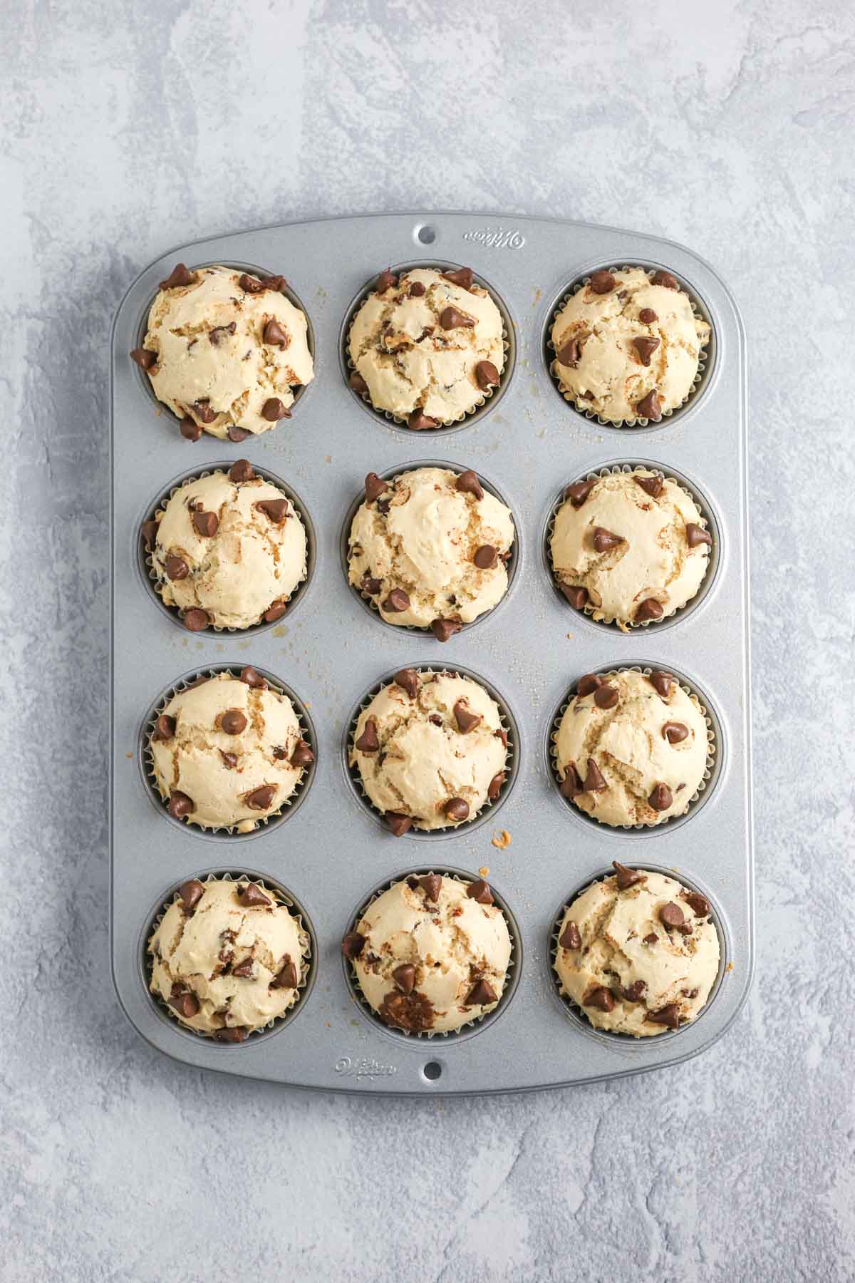 baked muffins risen in the muffin tin with golden brown tops.