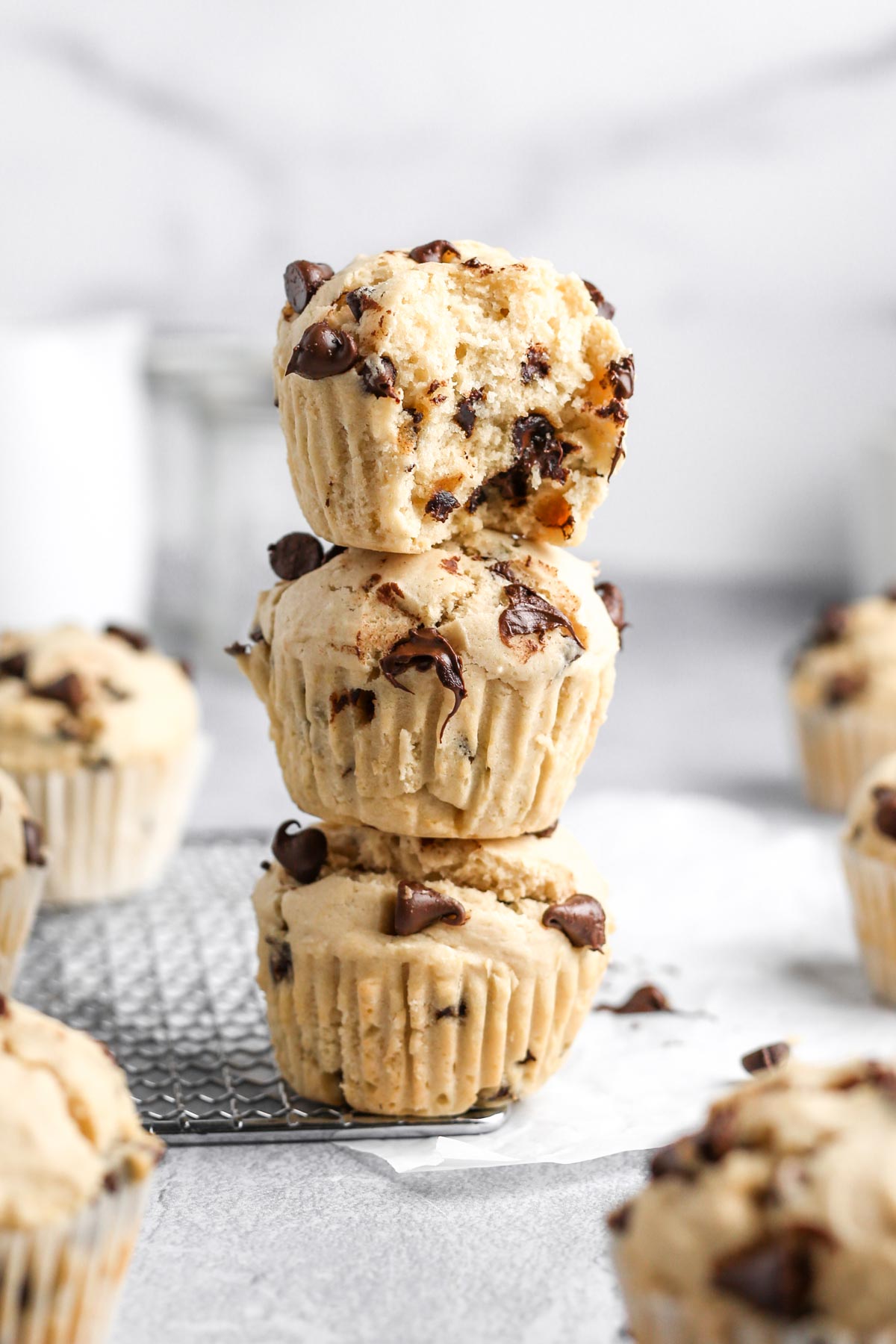 a stack of three super fluffy chocolate chip muffins on a marble surface.