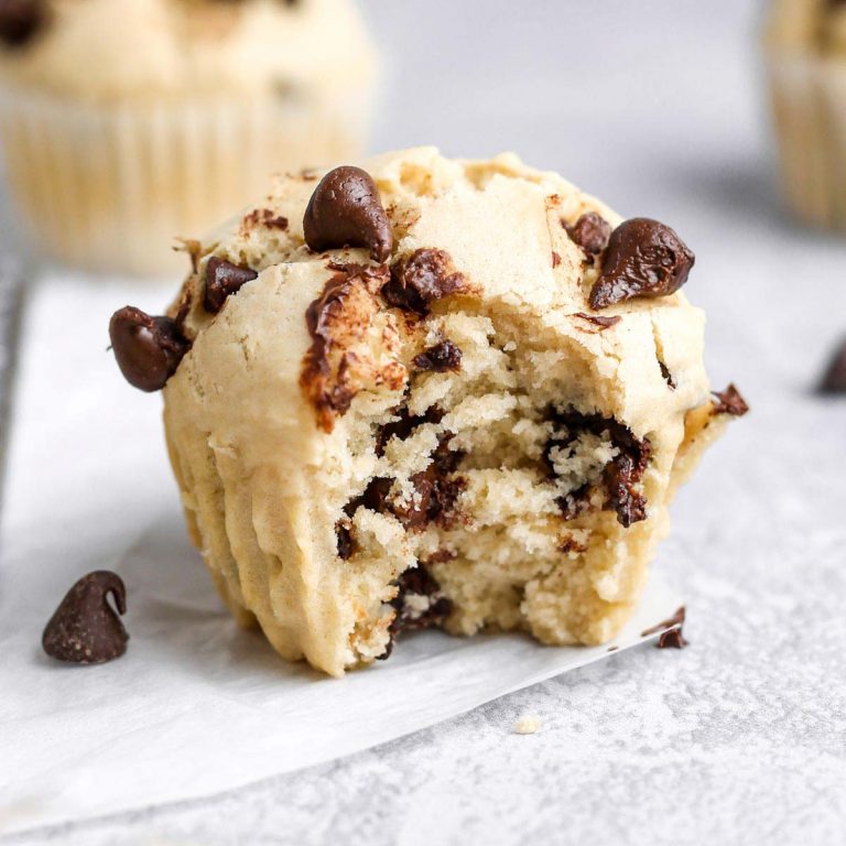 a dairy-free chocolate chip muffin on parchment paper with a bite taken out of the side.