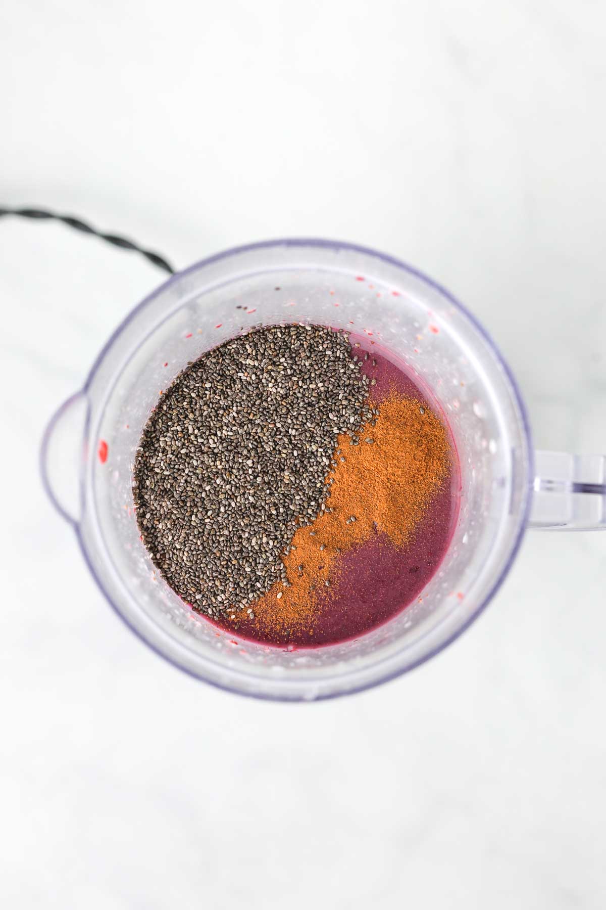 adding the chia seeds and ground cinnamon to the smoothie in the blender.