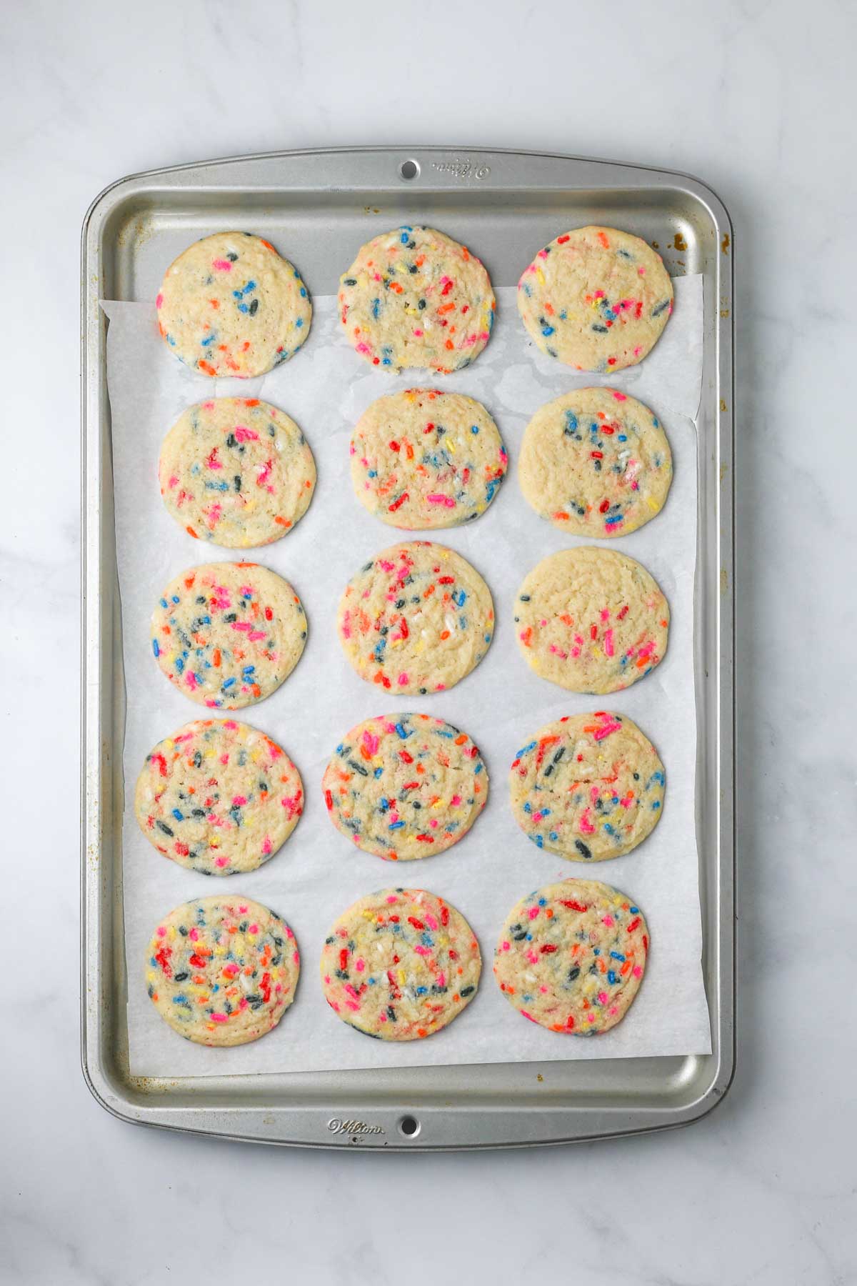 a large baking sheet with baked funfetti sugar cookies.