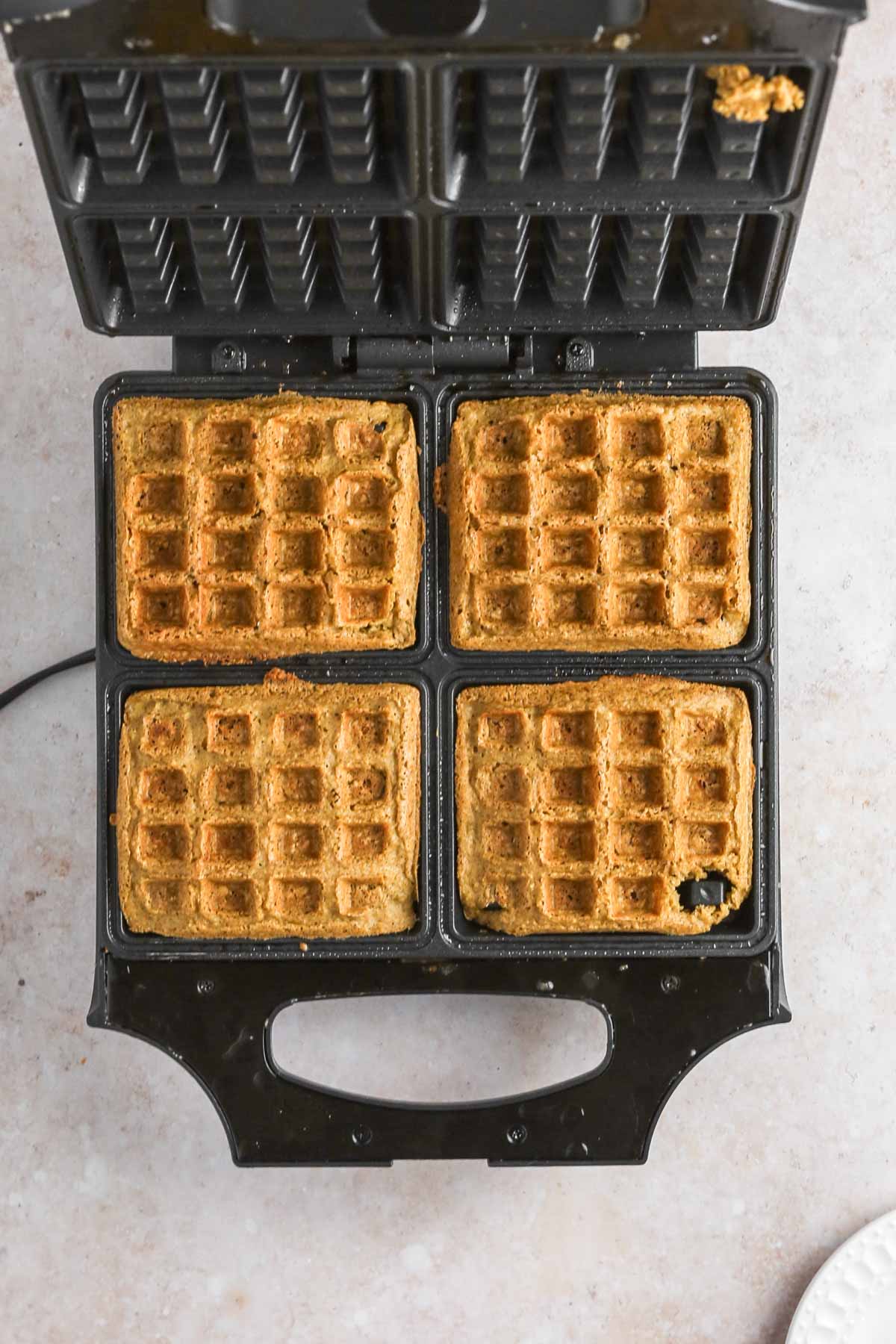 cooked, golden-brown waffles in the waffle iron before being removed.