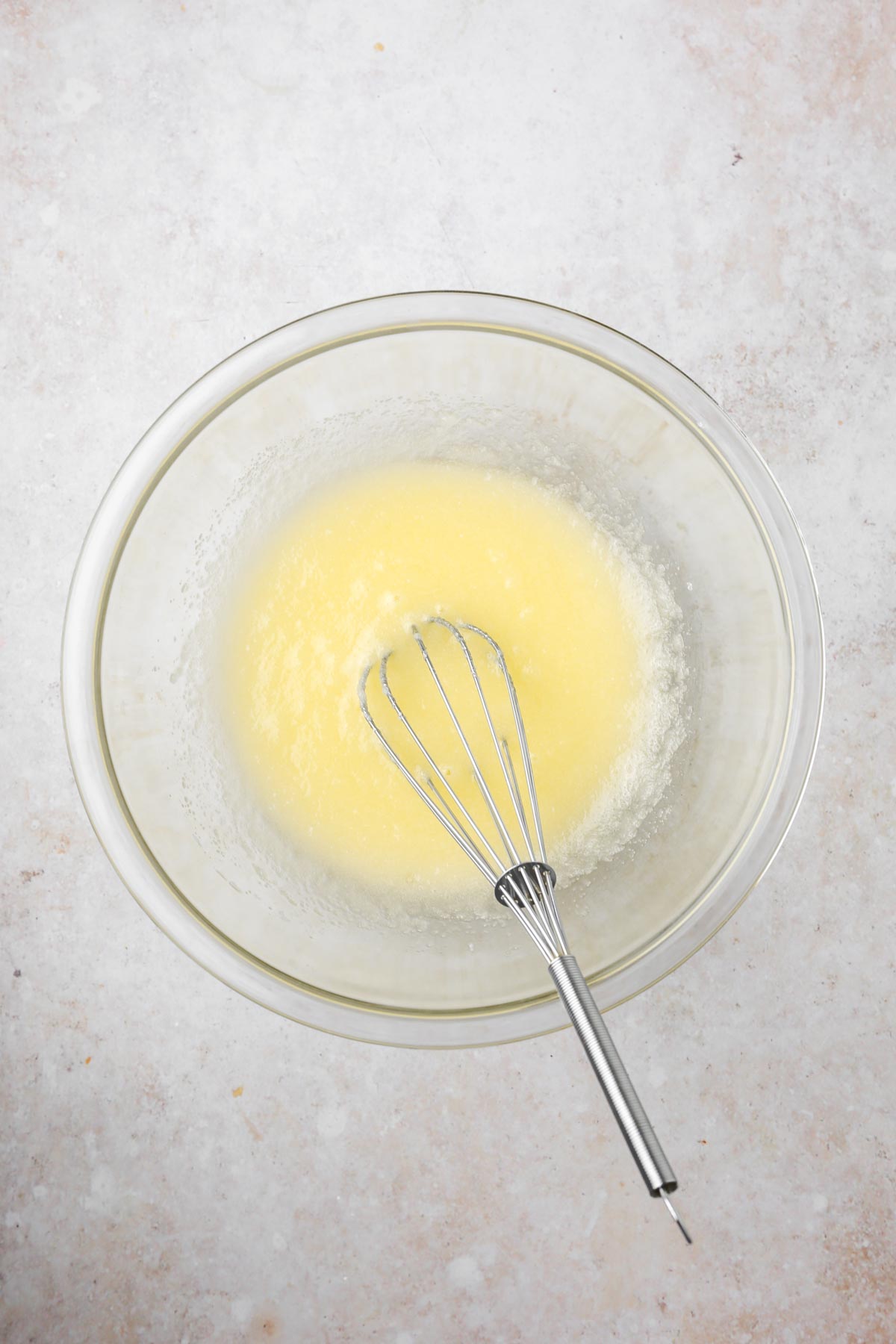 Whisking the vegan butter, sugar, applesauce, vanilla, and almond milk into a creamy yellow mixture.