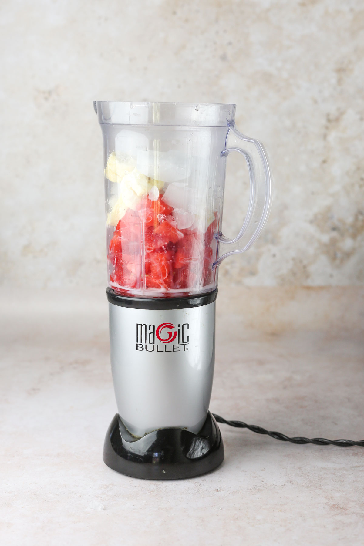 adding the watermelon, banana, and ice to a blender.
