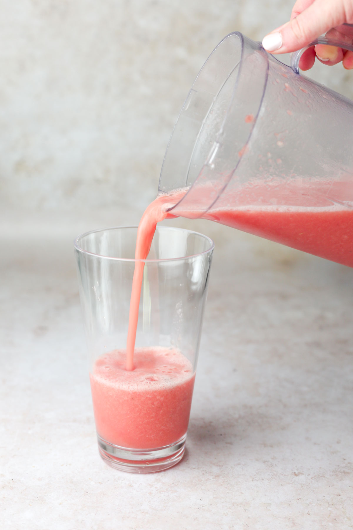 pouring the smoothie into a separate glass for serving.