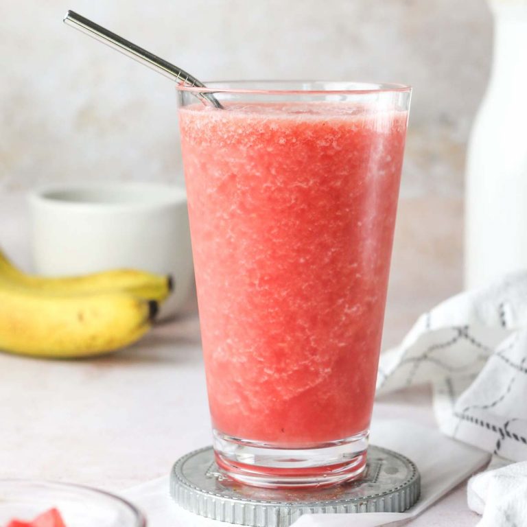 healthy pink watermelon banana smoothie in a glass with a straw.
