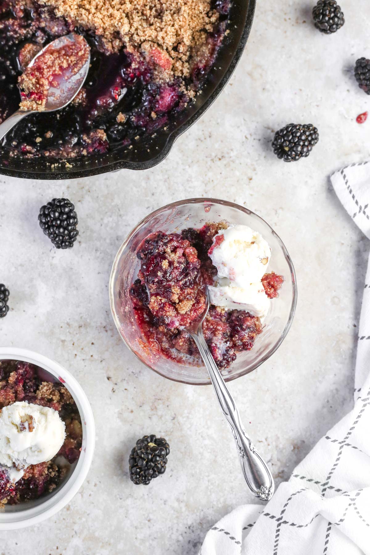 gluten-free blackberry cobbler with a spoon, being enjoyed and halfway eaten with ice cream.