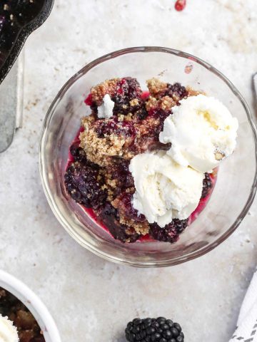 gluten-free blackberry cobbler in a clear dish with ice cream.