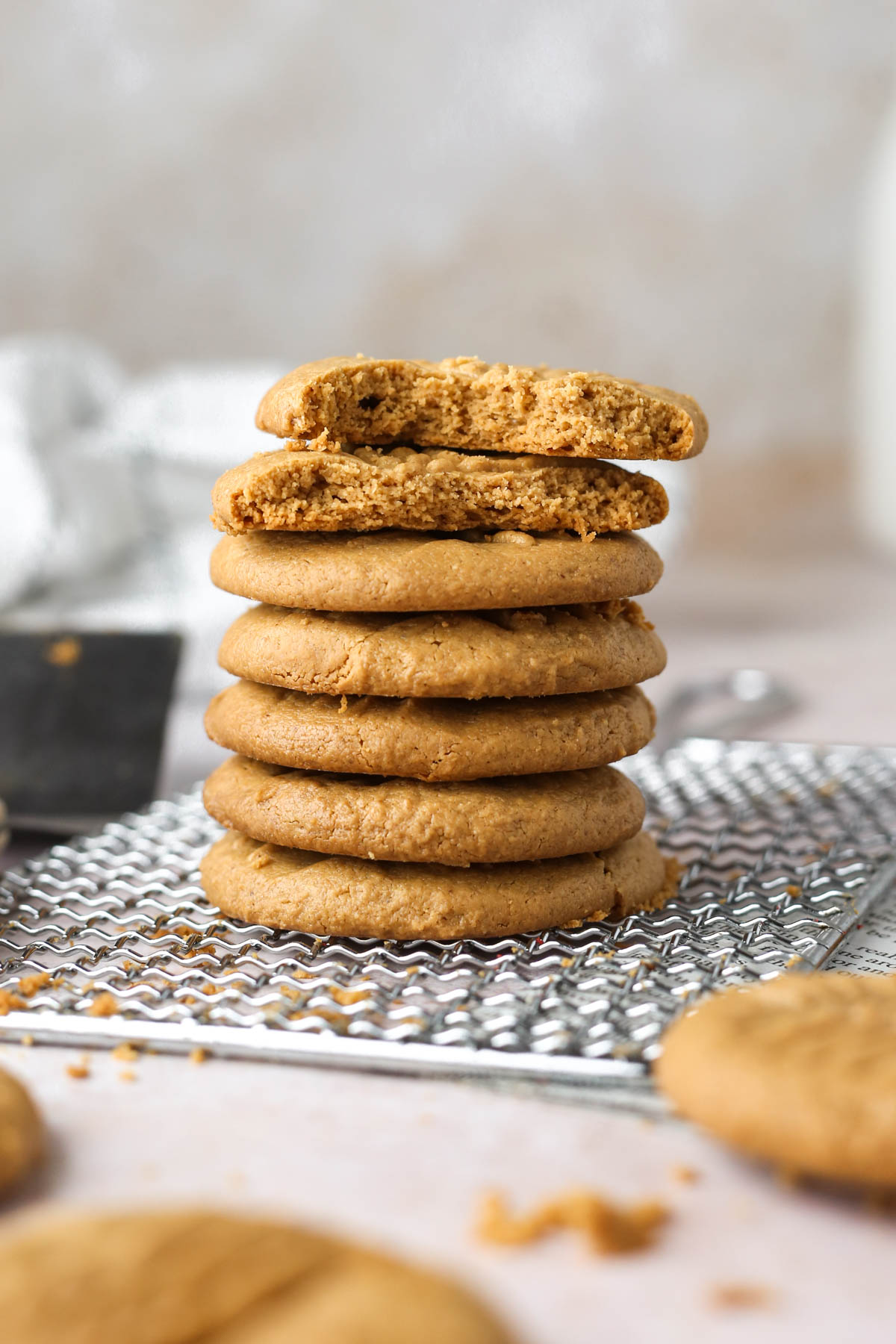 a stack of seven peanut butter cookies, with the top two cookies in the stack missing bites, showing the soft texture inside.
