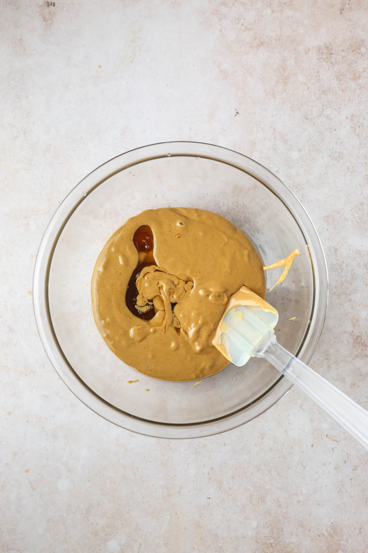 adding the maple syrup and peanut butter to a large mixing bowl with a spatula.
