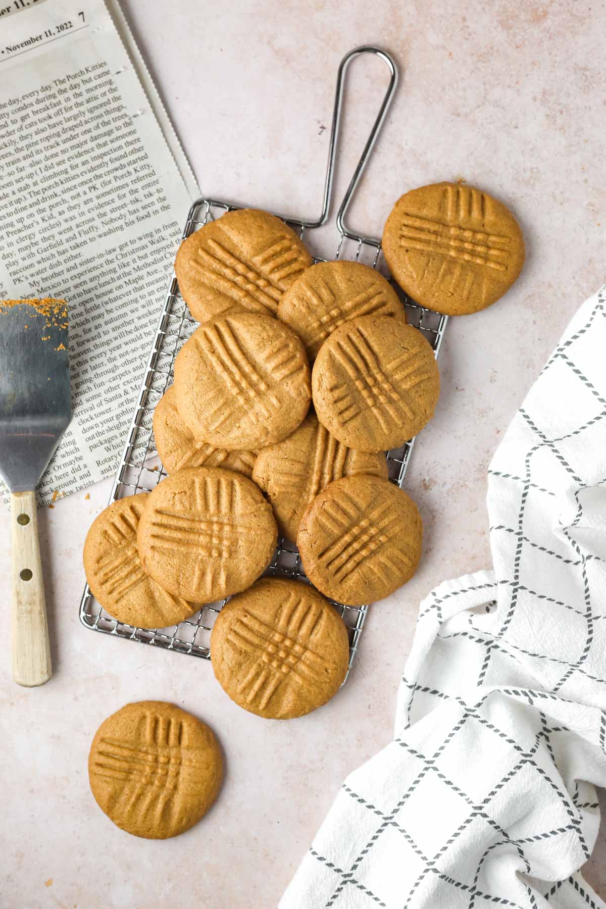 a dozen 2-ingredient peanut butter cookies shown from above on a wire rack, next to a spatula.