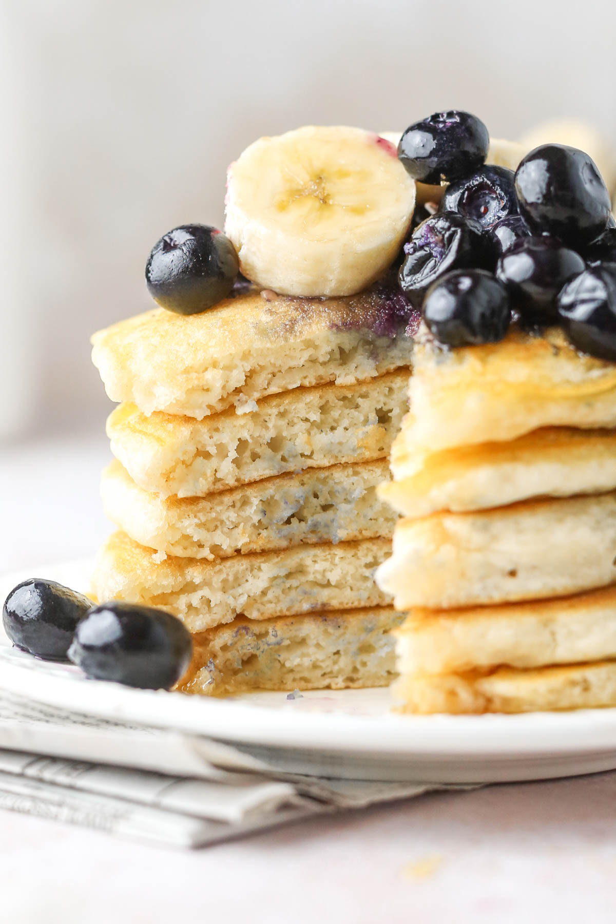 close up of a stack of oat milk pancakes with a portion cut out of the side, showing the soft and fluffy texture inside.