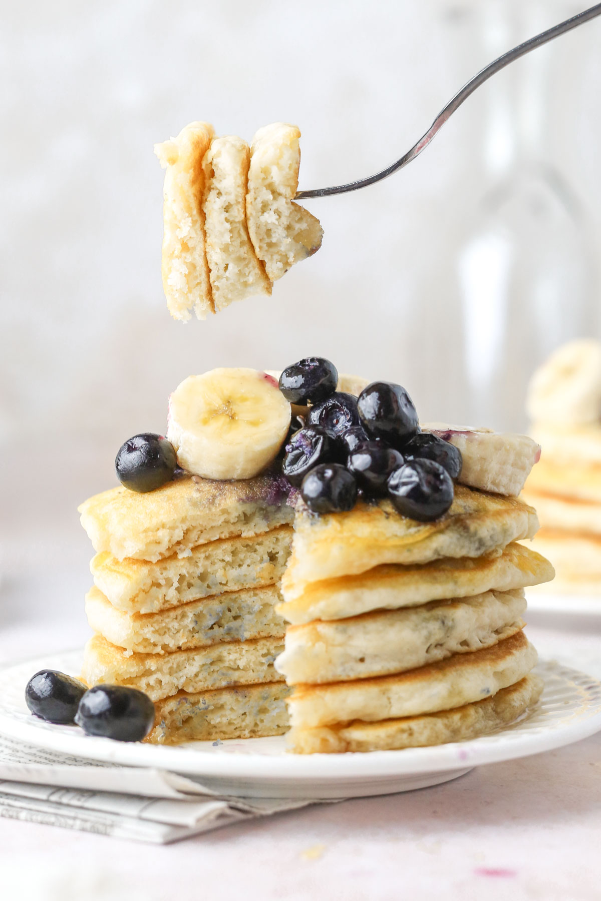 a stack of dairy-free pancakes shown from the side with a fork holding a chunk of pancakes over top the stack.