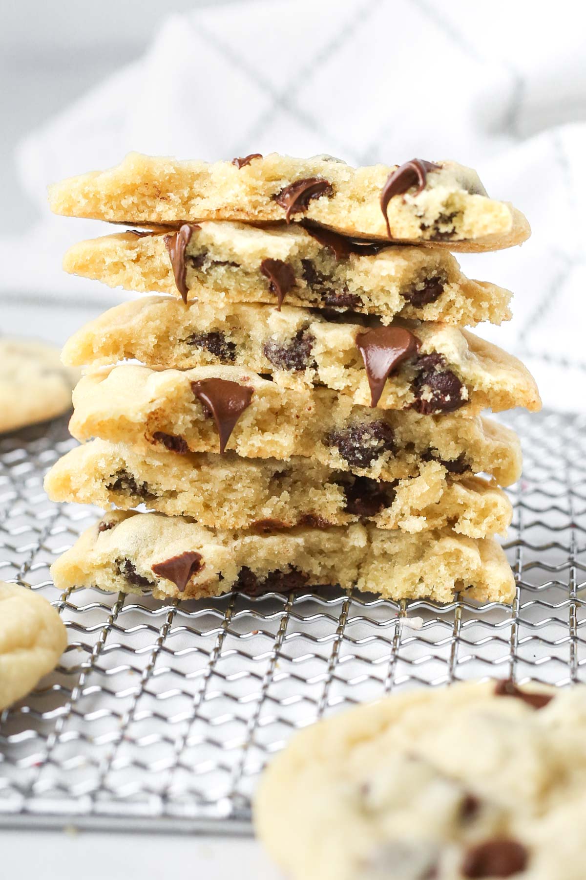 a stack of chocolate chip cookies in half, with melting chocolate chips coming out of the centers.