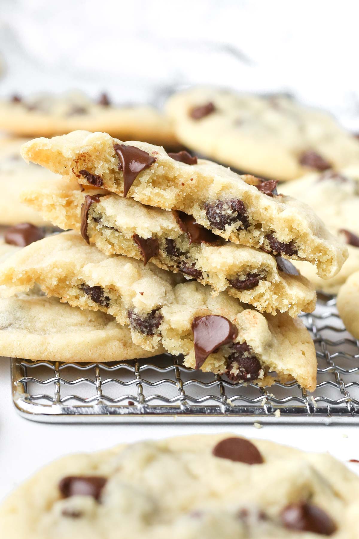 three chocolate chip cookies without brown sugar stacked on top of each other with melting chocolate coming out of the centers.