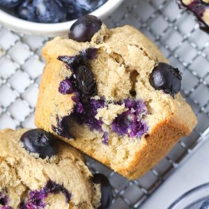 inside a banana blueberry oatmeal muffin with fresh blueberries coloring the inside of the muffins purple.