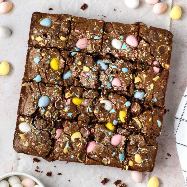 overhead view of cadbury mini egg brownies cut into squares on parchment paper.