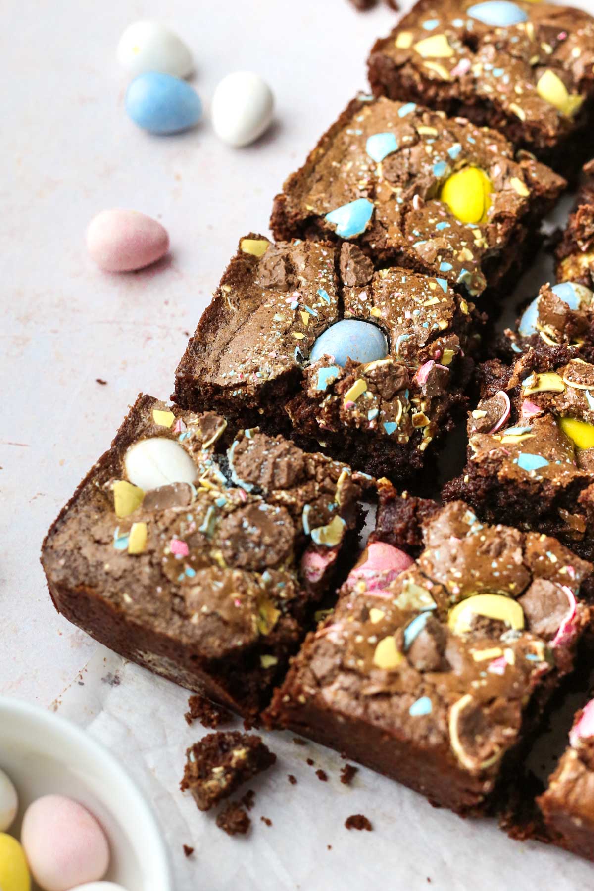 Angled shot of freshly cut brownies with colorful eggs baked into the top.