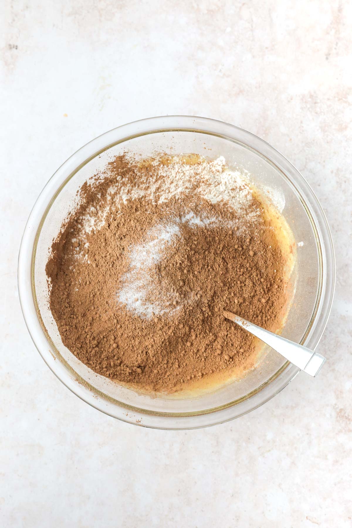 Cocoa powder and flour in a large mixing bowl with a spoon.