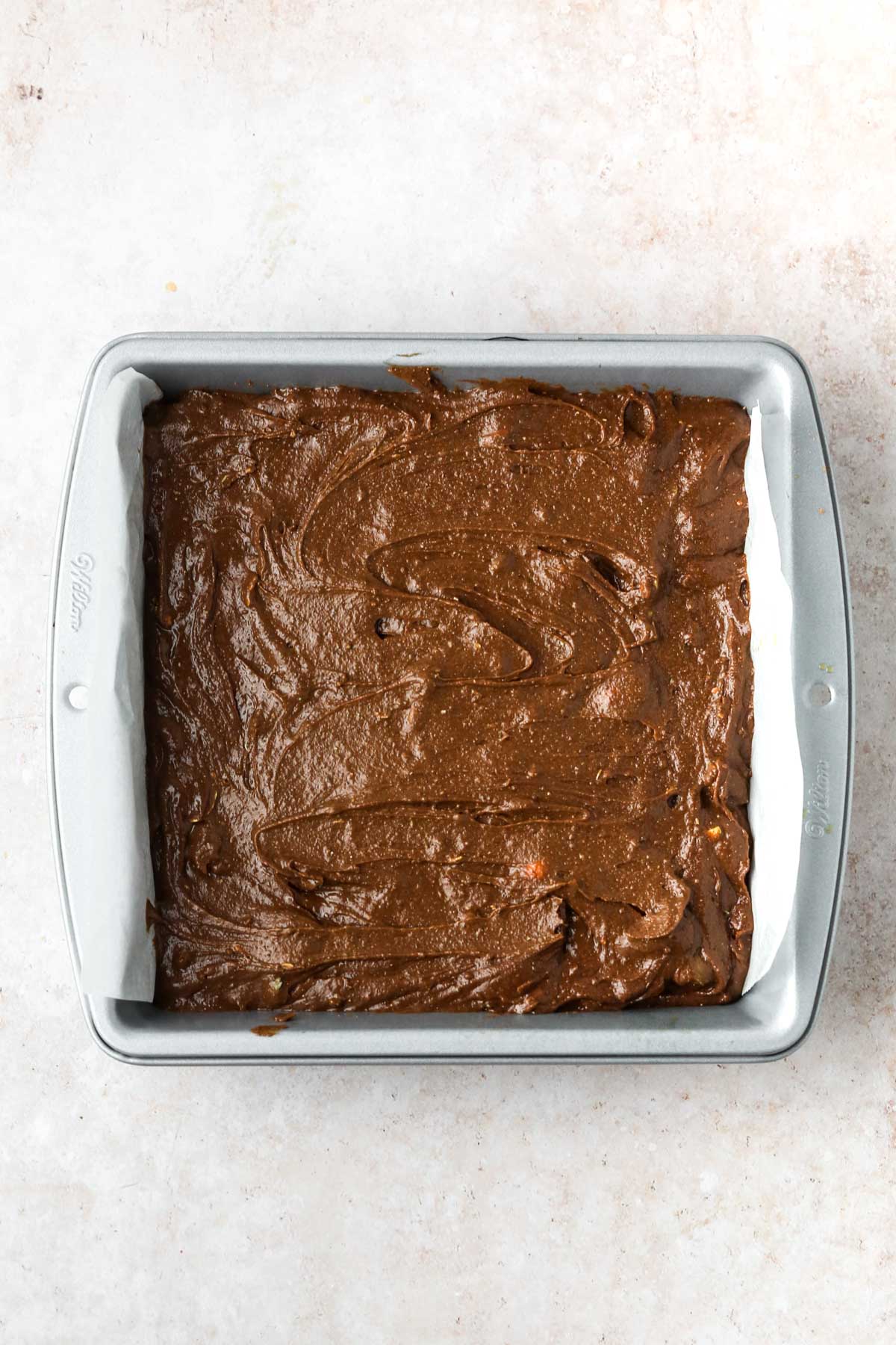 An 8x8" baking pan full of chocolate brownie batter.