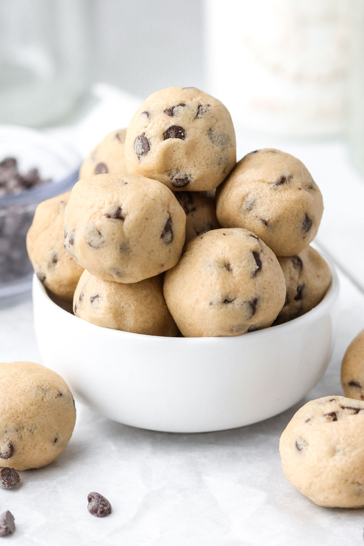 A small white bowl filled with a stack of no-bake cookie dough bites.