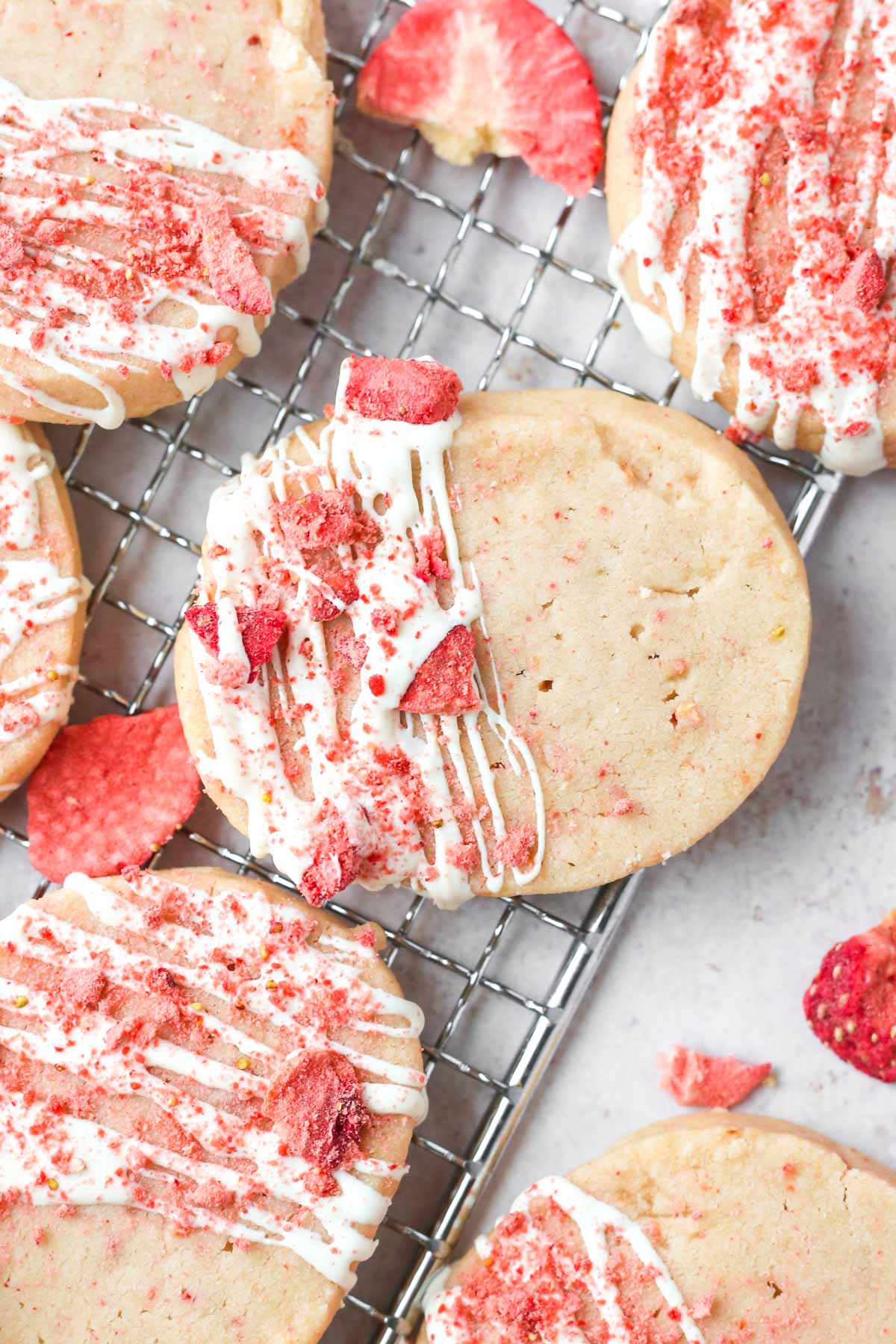 Baked shortbread cookie shown from above on a tray with a white chocolate drizzle and freeze-dried strawberries on top.