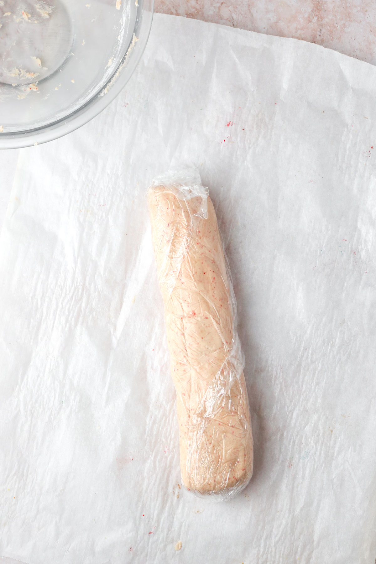 A log of cookie dough wrapped in plastic wrap for chilling in the fridge.