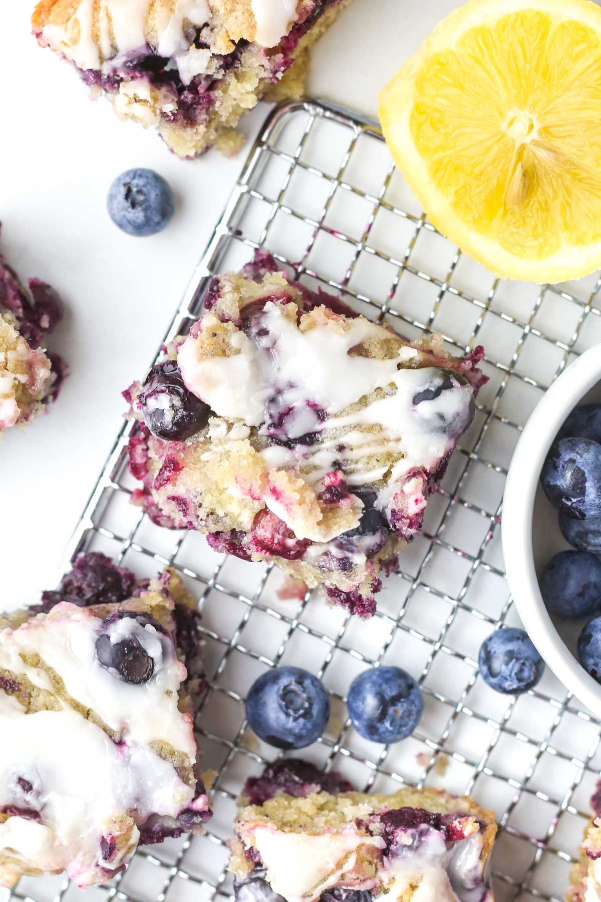 freshly baked blueberry lemon blondie bars shown from above with a lemon glaze on top.