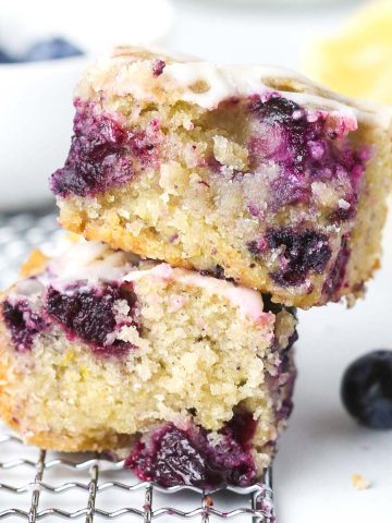 two lemon blueberry blondies stacked and shown from the side, with blueberries inside.